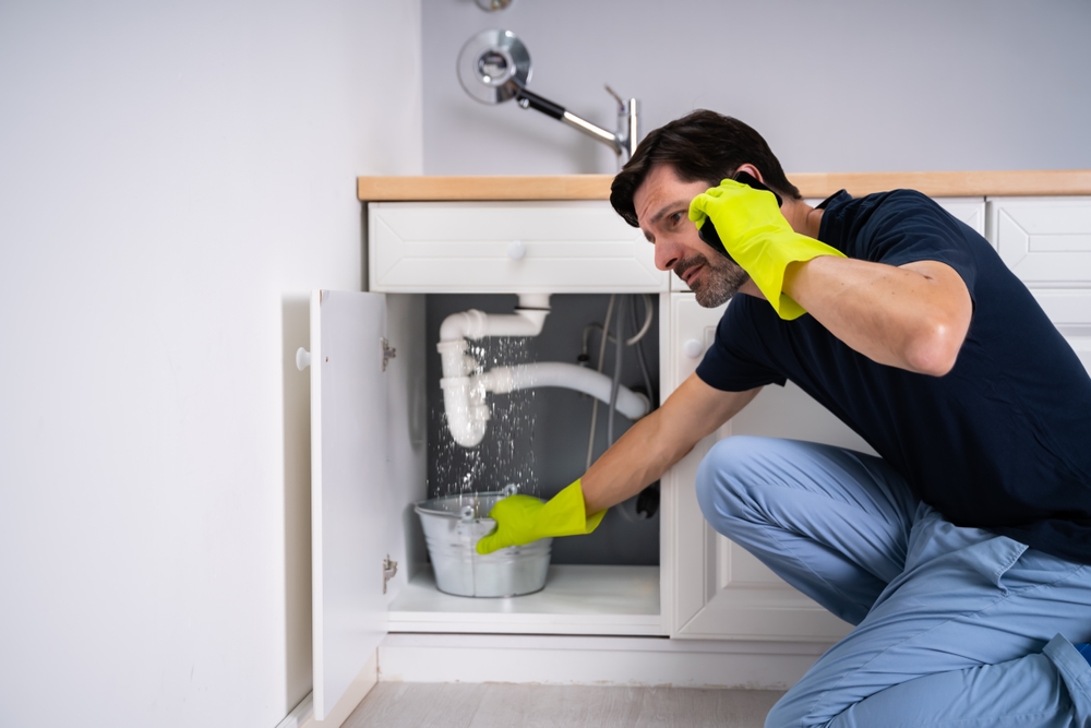 Man calling plumber in emergency for kitchen sink water leakage