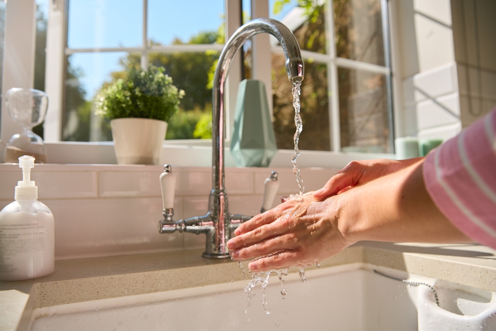 Woman washing hand using kitchen sink